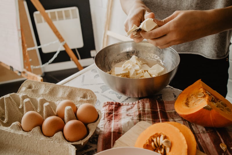 Person preparing food with eggs and pumpkins on a table